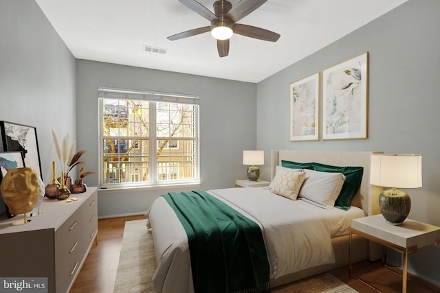 bedroom with a ceiling fan, wood finished floors, and visible vents