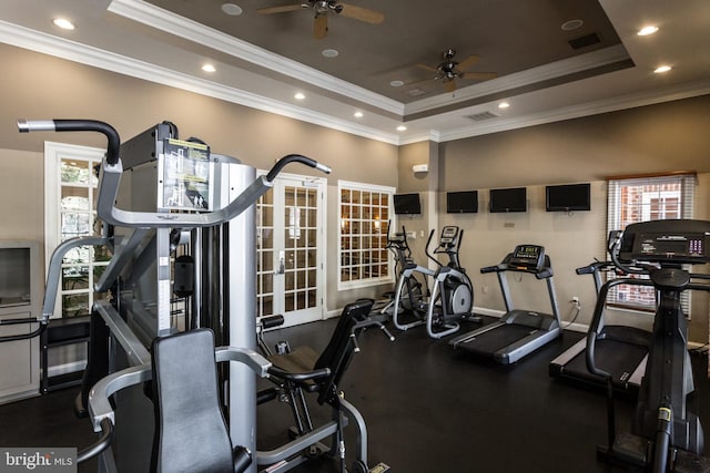 gym with visible vents, a tray ceiling, and ornamental molding