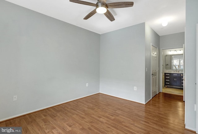 spare room featuring baseboards, wood finished floors, and a ceiling fan