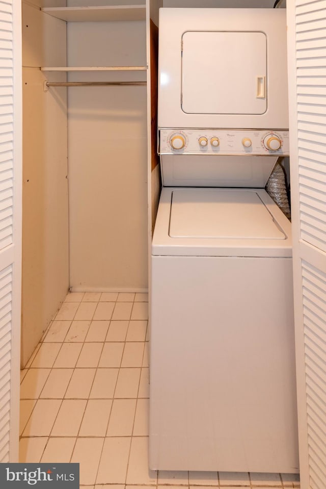 laundry room with laundry area, light tile patterned flooring, and stacked washer and clothes dryer