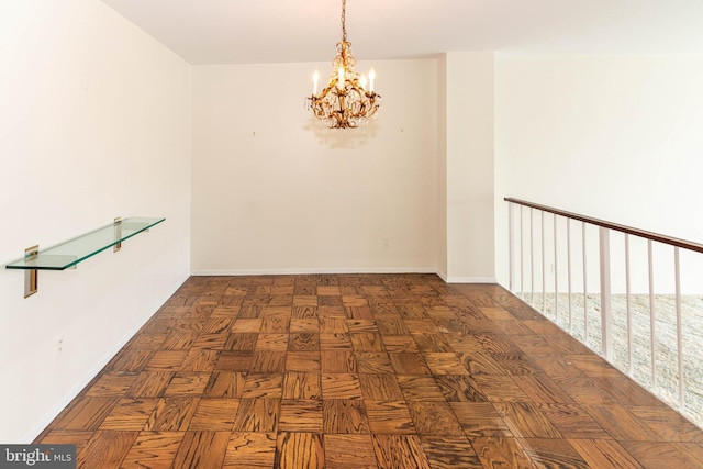 spare room featuring a notable chandelier and baseboards