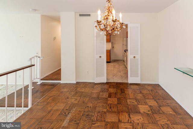 spare room featuring visible vents, baseboards, and an inviting chandelier