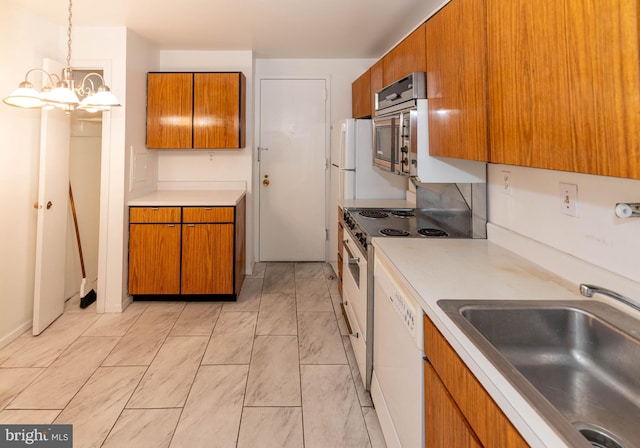 kitchen featuring brown cabinetry, light countertops, white dishwasher, and a sink