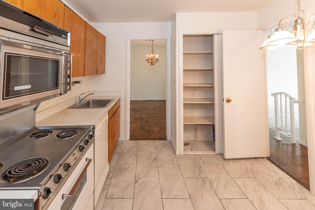 kitchen with brown cabinets, a sink, an inviting chandelier, range, and dishwasher