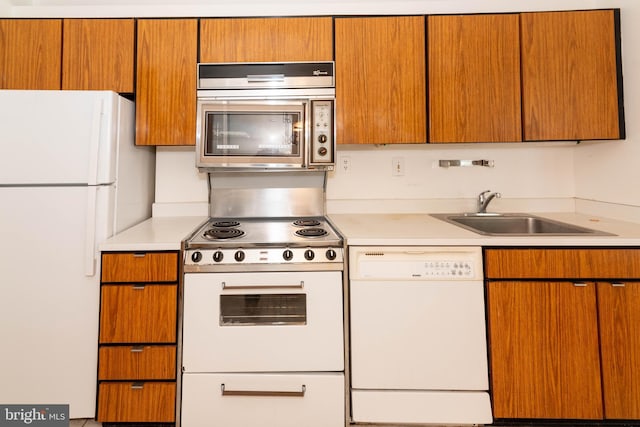 kitchen featuring white appliances, light countertops, and a sink