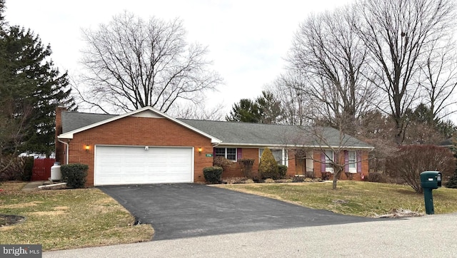 ranch-style house with a front yard, brick siding, an attached garage, and driveway