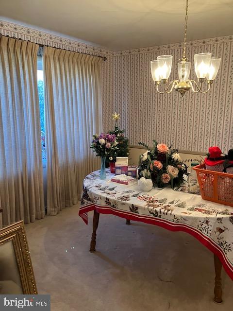 carpeted dining space with a chandelier and wallpapered walls