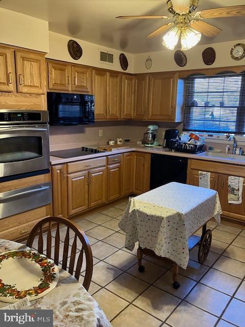 kitchen featuring visible vents, light countertops, black appliances, a warming drawer, and a sink