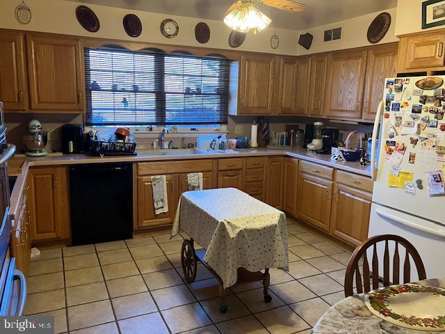 kitchen featuring visible vents, dishwasher, light countertops, light tile patterned floors, and freestanding refrigerator