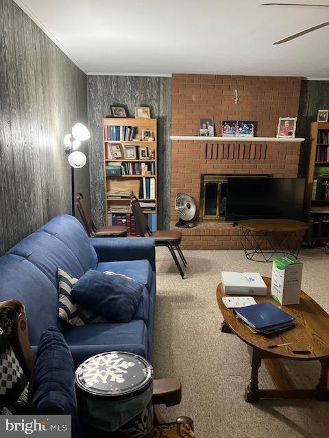 carpeted living area with wood walls, a fireplace, and crown molding