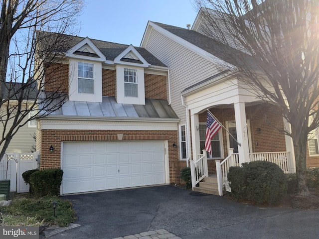 view of front of home featuring a standing seam roof, aphalt driveway, covered porch, and brick siding