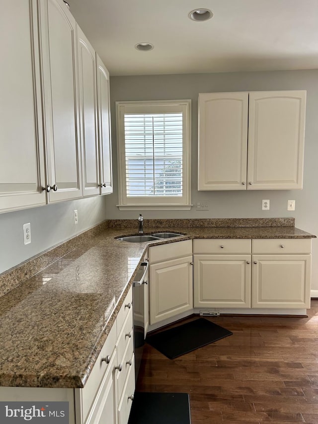 kitchen with a sink, dark wood-style floors, white cabinets, and dark stone countertops