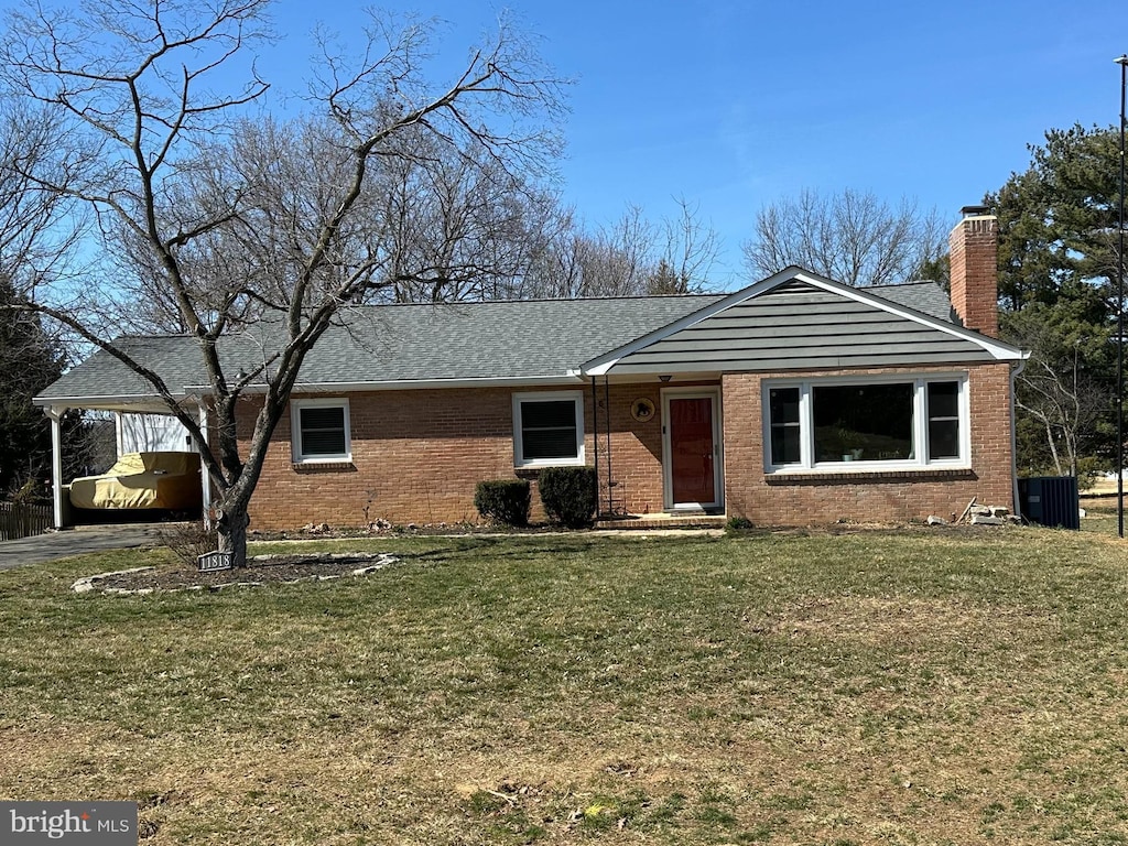 ranch-style house featuring an attached carport, central AC unit, a chimney, a front lawn, and brick siding