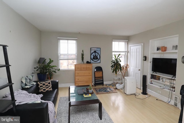 living room with visible vents, baseboards, and wood finished floors