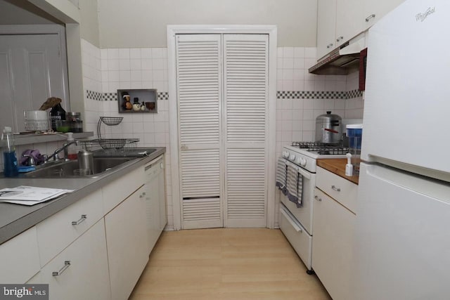 kitchen with a sink, white appliances, light wood-style flooring, and white cabinetry