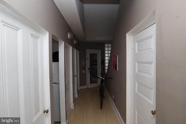 corridor with light wood-style floors and baseboards