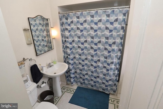 bathroom with tile patterned flooring, toilet, a shower with shower curtain, and a sink