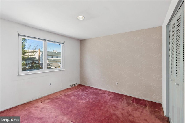 unfurnished bedroom featuring recessed lighting, visible vents, a closet, and carpet floors