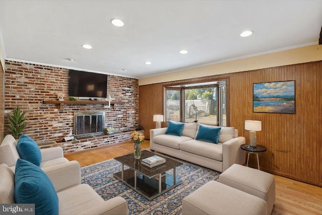 living area with wood finished floors, brick wall, crown molding, a fireplace, and wood walls