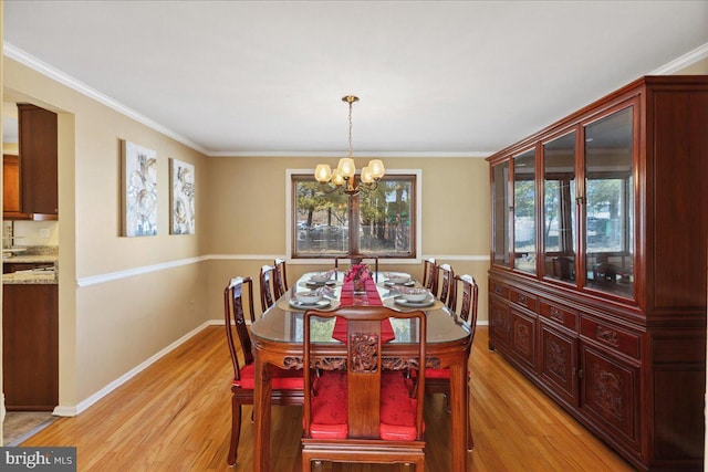 dining room featuring light wood finished floors, a chandelier, crown molding, and baseboards