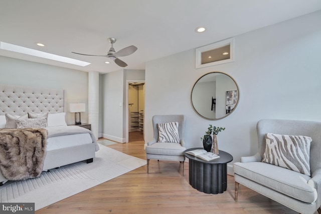 bedroom featuring a ceiling fan, a skylight, recessed lighting, and wood finished floors