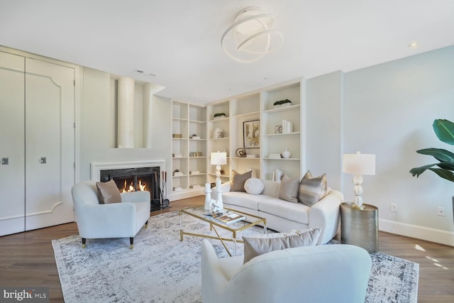 living area with a fireplace with flush hearth, wood finished floors, visible vents, and baseboards