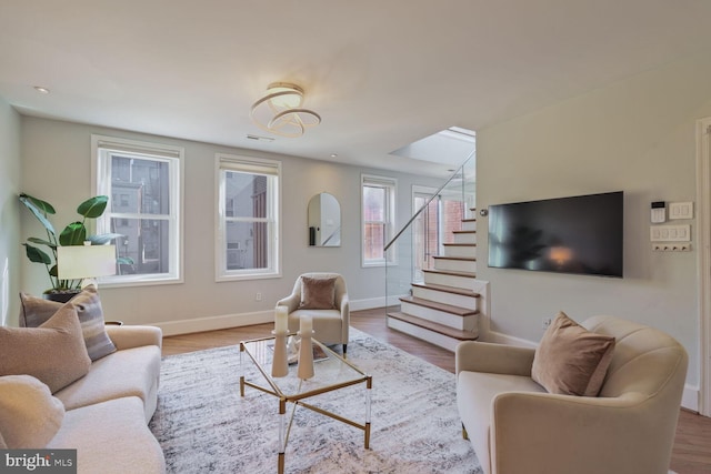 living room with stairs, wood finished floors, and baseboards