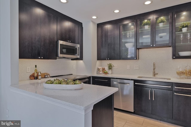 kitchen with backsplash, stainless steel appliances, glass insert cabinets, and a sink