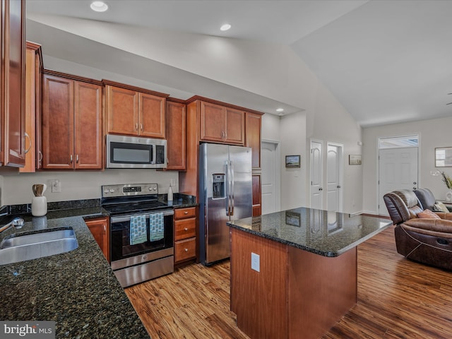 kitchen with open floor plan, appliances with stainless steel finishes, light wood-type flooring, and a sink