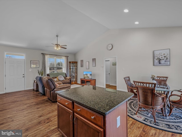 kitchen with open floor plan, wood finished floors, a center island, ceiling fan, and vaulted ceiling