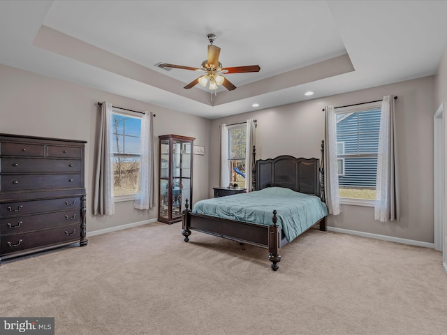 bedroom with a tray ceiling, baseboards, and light colored carpet