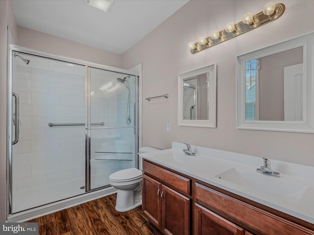 full bathroom with a sink, toilet, a stall shower, and wood finished floors