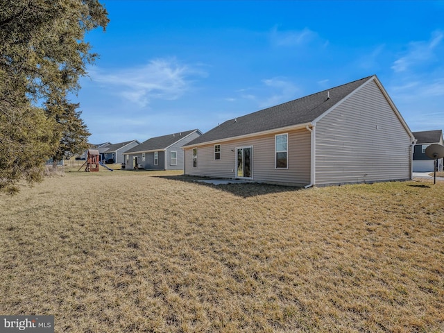 rear view of property featuring a playground and a yard