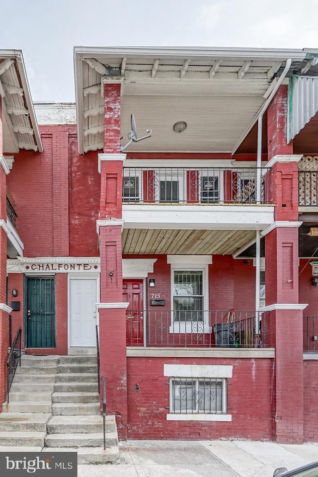 view of front of property featuring entry steps, a balcony, and brick siding