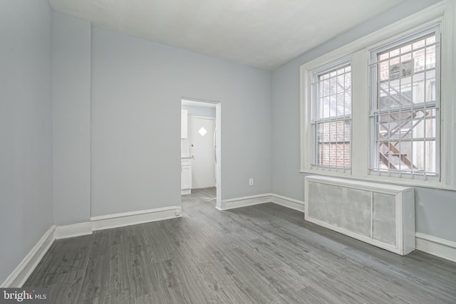 unfurnished room with dark wood finished floors and baseboards