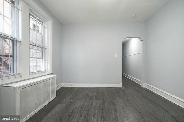 spare room featuring dark wood finished floors and baseboards