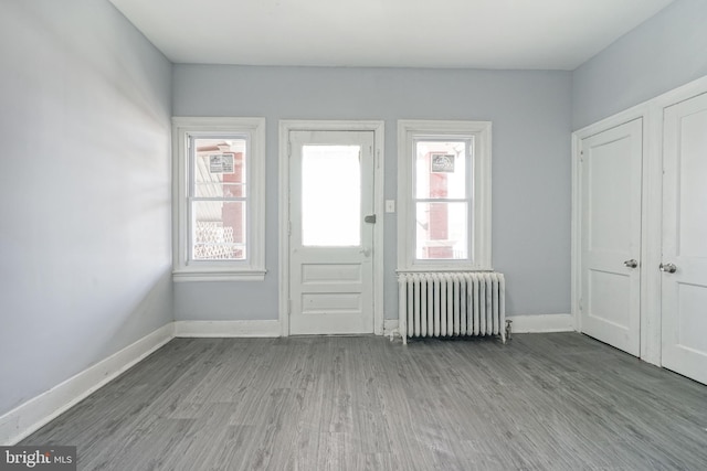 doorway with baseboards, radiator, and wood finished floors