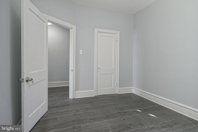 unfurnished room with dark wood-style floors and baseboards