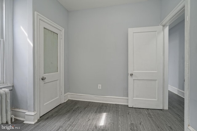 unfurnished bedroom featuring radiator, baseboards, and wood finished floors