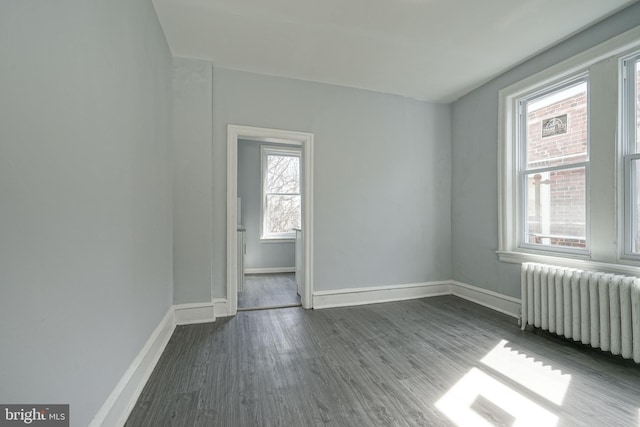 spare room featuring radiator, dark wood-style floors, and baseboards