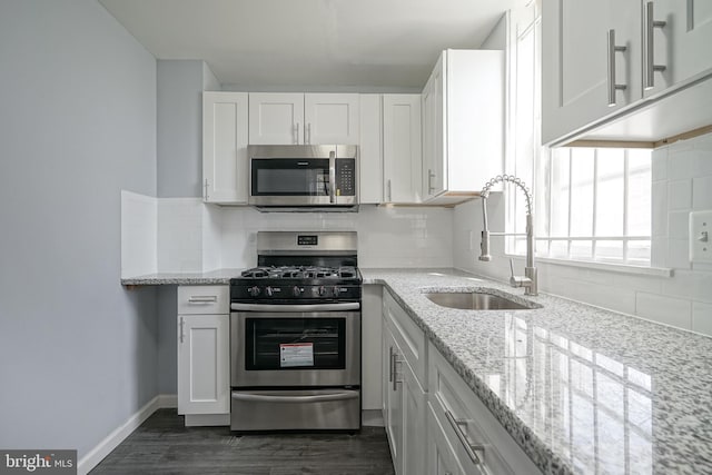 kitchen featuring a sink, backsplash, appliances with stainless steel finishes, and white cabinets