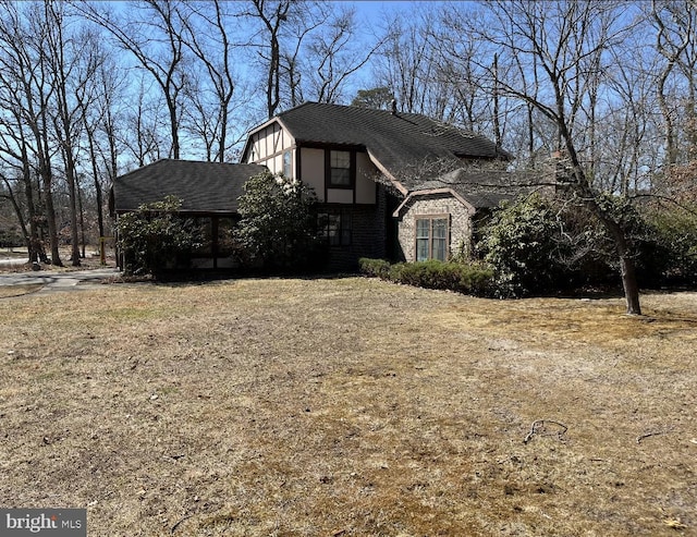 tudor home featuring brick siding and a shingled roof