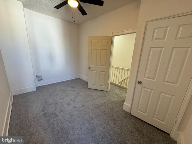 unfurnished bedroom with visible vents, a textured ceiling, carpet flooring, baseboards, and vaulted ceiling