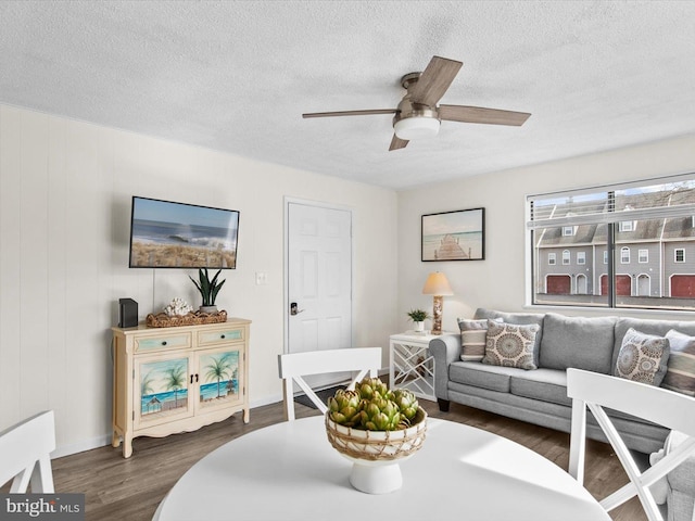 living room featuring a ceiling fan, dark wood-style flooring, and a textured ceiling