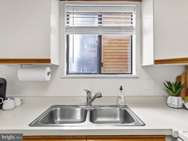 room details with a sink, white cabinets, and light countertops