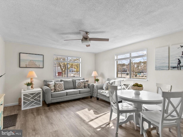 dining room featuring ceiling fan, baseboards, a textured ceiling, and wood finished floors