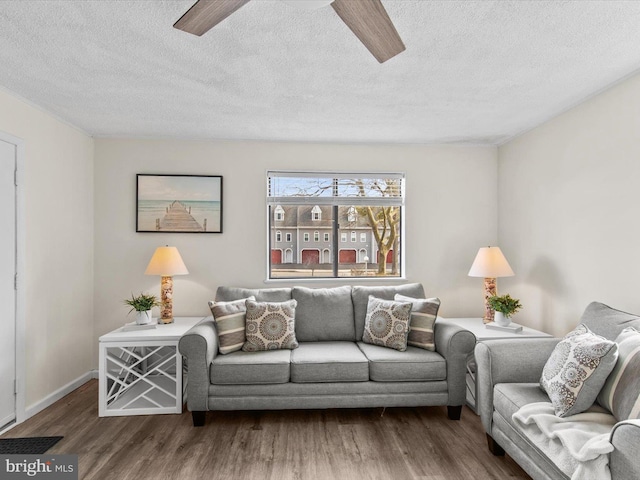 living room featuring a textured ceiling, wood finished floors, baseboards, and ceiling fan