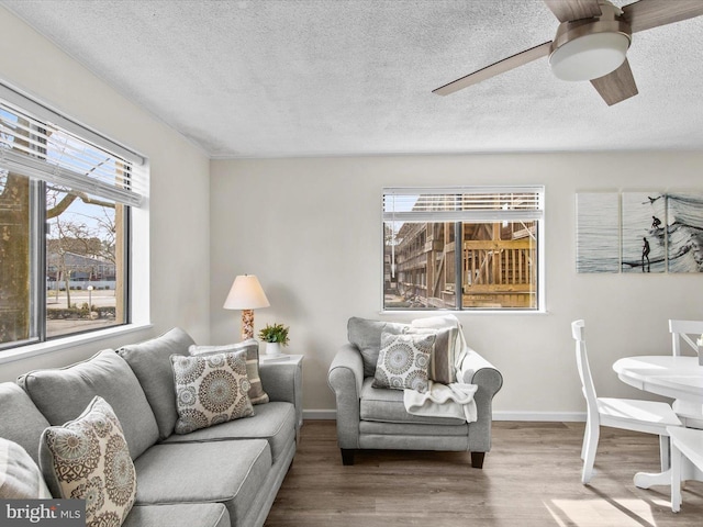 living area featuring a wealth of natural light, baseboards, wood finished floors, and ceiling fan