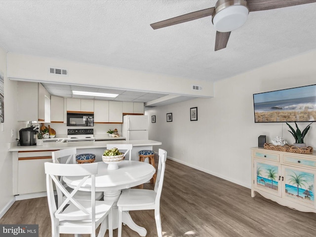 dining space featuring visible vents, a textured ceiling, baseboards, and wood finished floors