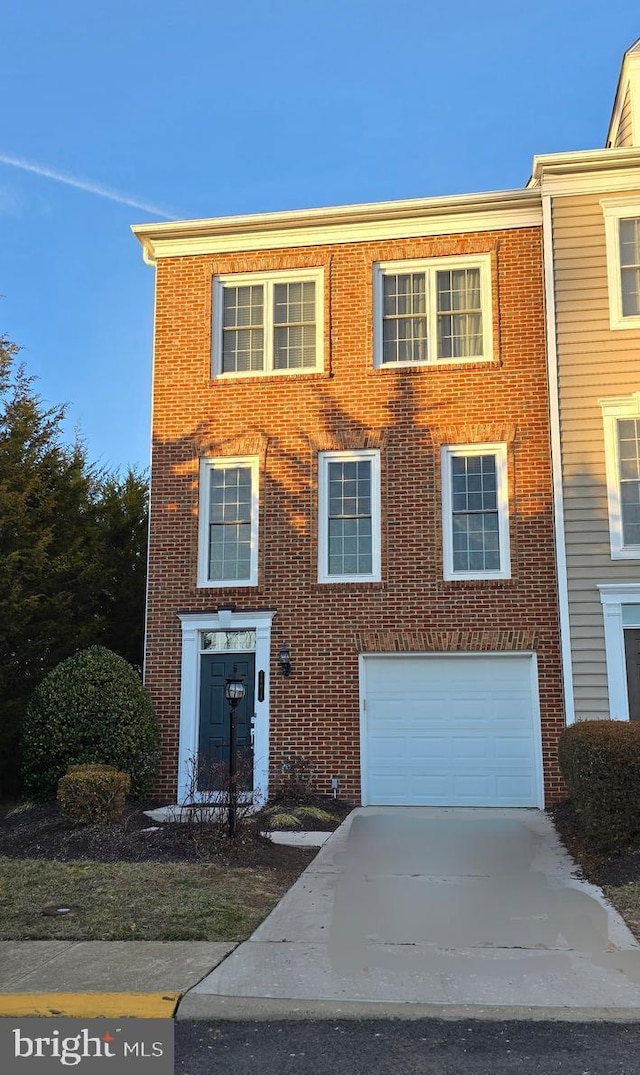 view of property with an attached garage, brick siding, and driveway